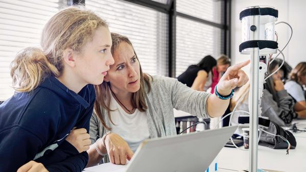 Photo of the pupil Mina and her mentor Stefanie Burri (civil engineer) while programming a robot arm.