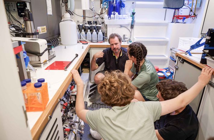 Meeres-Chemiker Hans Slagter erklärt den Hochsee-Praktikantinnen die unter dem Labortisch installierte FerryBox, die eine detaillierte Charakterisierung der Ökologie des oberen Ozeanwassers erstellt.